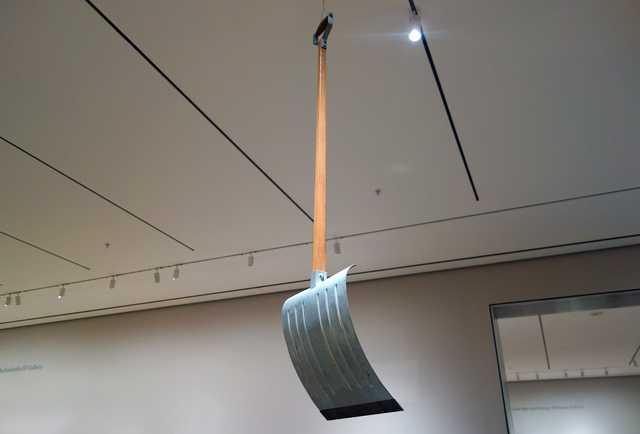 A snow shovel hanging from from the ceiling by a wire